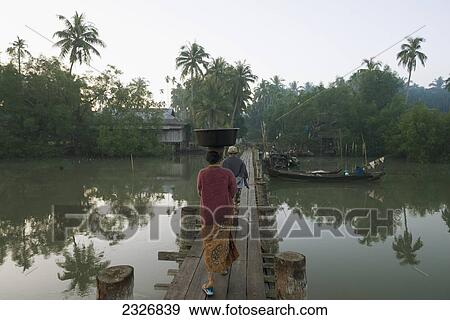 Stock Photo - Myanmar (Burma), Irrawaddyi division, Women crossing wooden bridge over river; Nag Yoke kaung village. Fotosearch