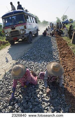 Stock Image - Myanmar (Burma), Road from Myaung Mya to Pathein; Irrawaddyi division, Female workers on road work site. Fotosearch