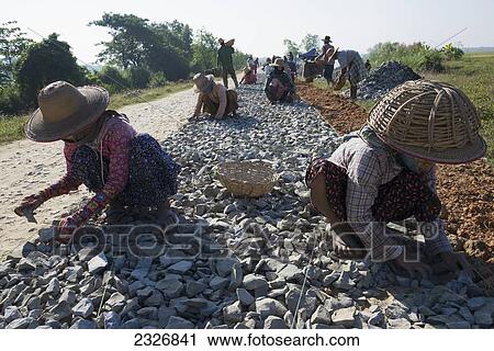 Stock Image - Myanmar (Burma), Road from Myaung Mya to Pathein; Irrawaddyi division, Female workers on road work site. Fotosearch