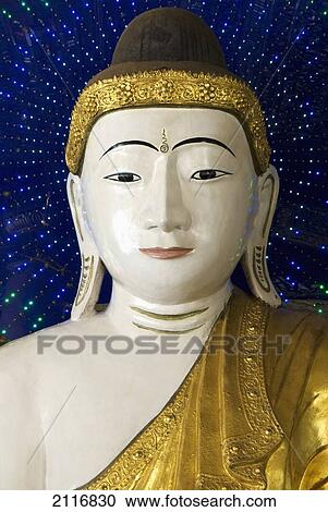 Stock Image - Myanmar, Yangon, Shwedagon, Paya, Head of a Buddha statue against blue background.. Fotosearch