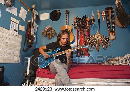 Native American boy playing guitar in bedroom; Rossburn, Manitoba, Canada View Large Photo Image Stock Image - Native American boy playing guitar in bedroom; Rossburn, Manitoba, Canada. Fotosearch