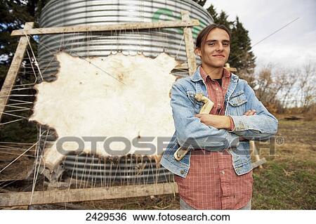Stock Photograph - Native American boy standing in front of a stretched buffalo hide; Rossburn, Manitoba, Canada. Fotosearch