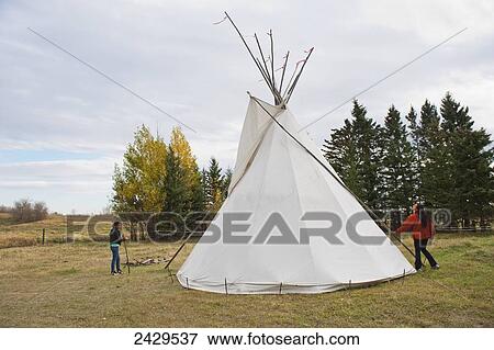 Native American girl and mother preparing a teepee; Rossburn, Manitoba, Canada View Large Photo Image Stock Photo - Native American girl and mother preparing a teepee; Rossburn, Manitoba, Canada. Fotosearch