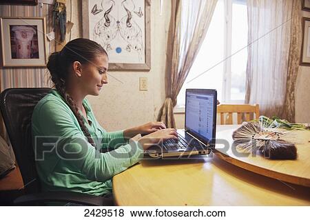 Stock Photo - Native American teenaged girl using a laptop computer at home; Rossburn, Manitoba, Canada. Fotosearch