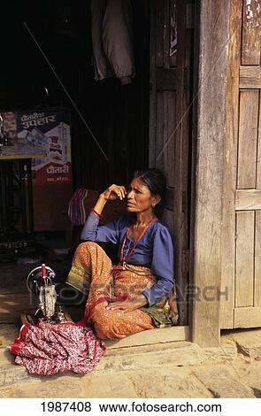Stock Photo - Nepal, Gorkha, Village Woman Sitting On Doorstep, Sewing Machine On Floor With Clothing. Editorial Use Only.. Fotosearch