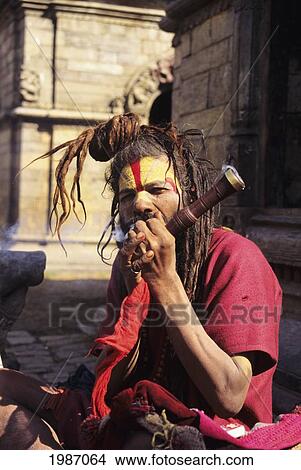 Picture - Nepal, Kathmandu, Pashupatinath Temple, Hindu Holy Man Smoking Pipe On Roadside, Dreadlocks Knotted On Top Of Head. Editorial Use Only.. Fotosearch