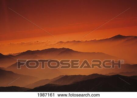 Stock Image - Nepal, Kathmandu Valley, Overhead View Of Hill Tops Silhouetted Among Orange Haze And Sky.. Fotosearch