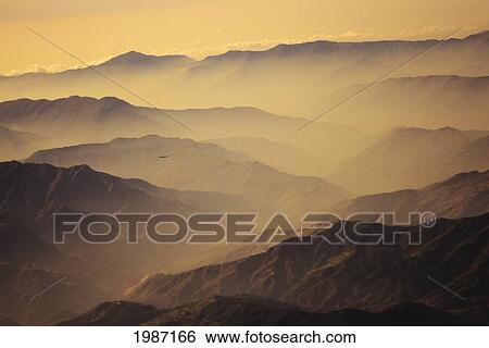 Stock Photograph - Nepal, Kathmandu Valley, Overhead View Of Hill Tops Silhouetted Among Yellow Haze And Sky.. Fotosearch