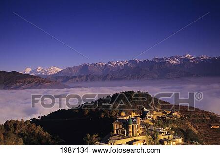 Picture - Nepal, Nagarkot, Overview Of Niva Lodge On Hillside, Cloud Line And Himalayan Range In Background.. Fotosearch