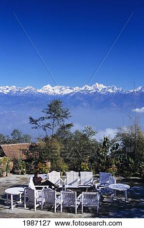 Nepal, Nagarkot, Woman Sitting In Courtyard Of Fort Hotel, Distant View Of Central Himalayas In Background. View Large Photo Image Stock Photo - Nepal, Nagarkot, Woman Sitting In Courtyard Of Fort Hotel, Distant View Of Central Himalayas In Background.. Fotosearch