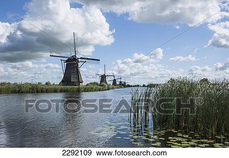 Stock Photo - Netherlands, Kinderjik, Windmills along water's edge. Fotosearch