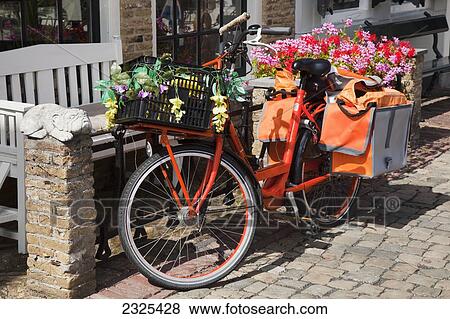 Stock Photo - Netherlands, Zealand, Bicycle with attached carrier and basket filled with flowers; Goes. Fotosearch