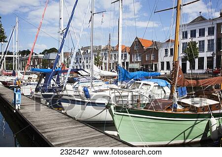 Netherlands, Zealand, Boats docked along wooden pier in harbour; Goes View Large Photo Image Stock Photo - Netherlands, Zealand, Boats docked along wooden pier in harbour; Goes. Fotosearch