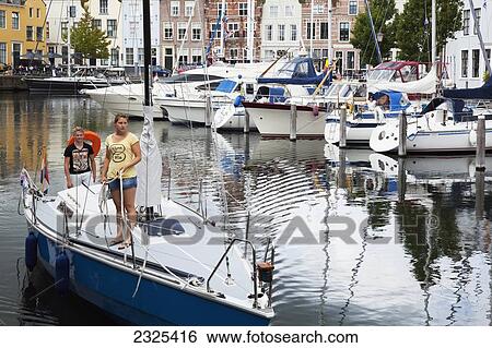 Netherlands, Zealand, Couple taking their sailboat out of harbour; Goes View Large Photo Image Stock Photograph - Netherlands, Zealand, Couple taking their sailboat out of harbour; Goes. Fotosearch