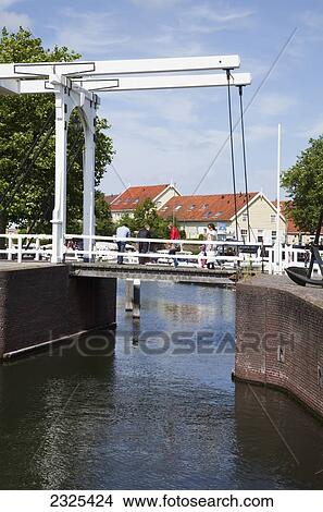 Picture - Netherlands, Zealand, People crossing passageway over water in harbour; Goes. Fotosearch