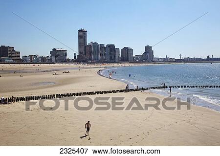 Stock Photo - Netherlands, Zealand, People on beach with view of town along coast in distance; Vlissingen. Fotosearch