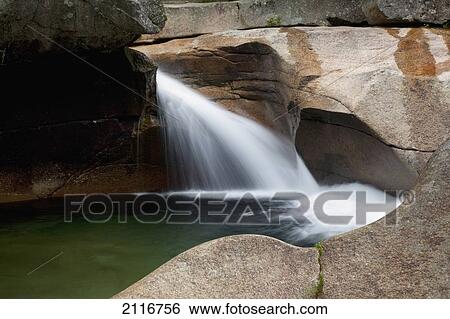 Stock Photograph - New England, New Hampshire, White Mountains, A forest riverbed and waterfall.. Fotosearch