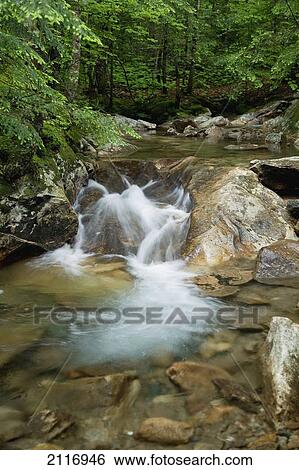 Stock Photograph - New England, New Hampshire, White Mountains, A rocky riverbed and waterfall.. Fotosearch