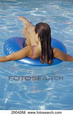 Stock Photo - New Jersey, Back View Of Woman Sitting In Blue Inner Tube In Pool. Fotosearch