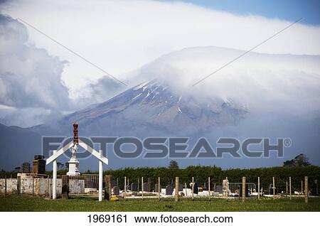 Stock Image - New Zealand, North Island, Taranaki, Maori Graveyard With A Wooden Gateway With Red Carving Figurine In Small Village, Okato.. Fotosearch
