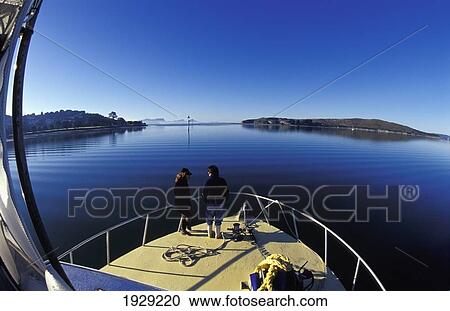 Stock Image - New Zealand, Northland, Couple on Foredeck Admiring Peaceful Calm of Windless Morning; Whangarei Harbor. Fotosearch