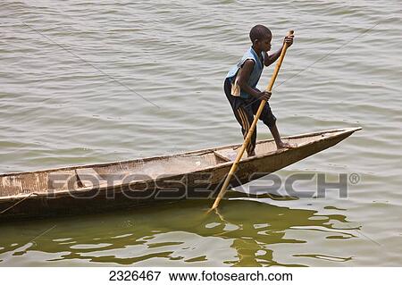 Stock Photo - Niger, Hausa fishermen boy cruising down Niger River on traditional pirogue; Niamey. Fotosearch
