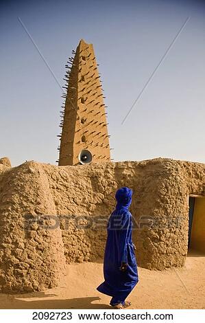 Stock Image - Niger, Sahara Desert, Agadez Region, built in 1515 but restored in 1844. It hosts renowed Centre of Islamic Studies and its 30 metres minaret is tallest mud-bricked minaret in Africa; Agadez, made of clay, Veiled Tuareg man walking past Grand Mosque. Fotosearch
