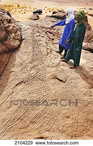 Niger, Sahara Desert, Agadez Region, Two Tuareg men examining the famous rock engravings of the Two Giant Giraffes of Dabous believed to be at least 6. 000 years old (belonging to the Chasseur Primitif or The Primitive Hunter Period); Dabous View Large Photo Image Stock Photo - Niger, Sahara Desert, Agadez Region, Two Tuareg men examining the famous rock engravings of the Two Giant Giraffes of Dabous believed to be at least 6. 000 years old (belonging to the Chasseur Primitif or The Primitive Hunter Period); Dabous. Fotosearch