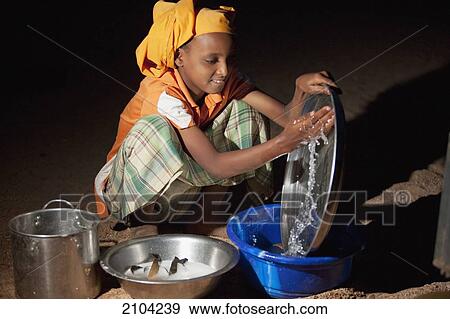 Stock Photo - Niger, Sahara Desert, Agadez Region, Tuareg girl washing up; Agadez. Fotosearch