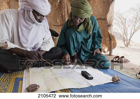 Stock Image - Niger, Sahara Desert, Escarpment of Tiguidit; Agadez Region, Tuareg men checking route's GPS points. Fotosearch