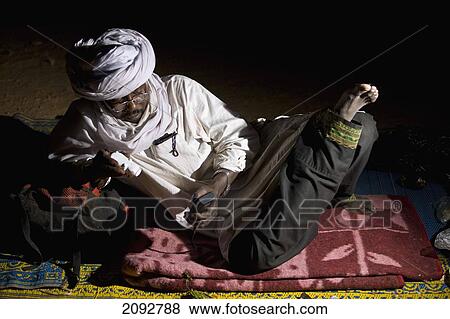Stock Photo - Niger, Sahara Desert, Escarpment of Tiguidit; Agadez Region, Tuareg guide checking GPS readings. Fotosearch