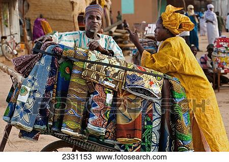 Stock Image - Niger, Tuareg men shopping for garments at Housa trader's stall. Agadez's livestock market; Agadez. Fotosearch