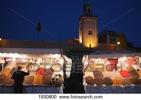 Stock Image - Night Time Shot Of Fruit And Nuts For Sale At A Street Stall On Djamaa El Fna, With Mosque In The Background, The Main Square In Marrakesh, Morocco; Marrakesh, Morocco. Fotosearch