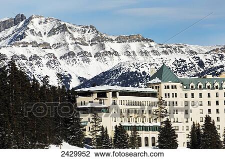 Stock Image - North side of the Chateau Lake Louise with snow covered mountain in the background and blue sky; Lake Louise, Alberta, Canada. Fotosearch
