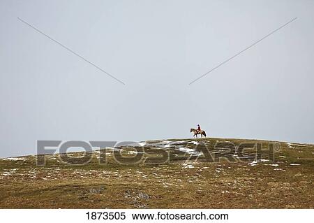 Northumberland, England; A Person Riding On A Horse At The Top Of A Hill With Traces Of Snow View Large Photo Image Stock Photography - Northumberland, England; A Person Riding On A Horse At The Top Of A Hill With Traces Of Snow. Fotosearch