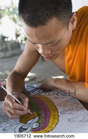 Stock Image - Novice Monk Drawing Pictures Of Buddha, Luang Prabang, Laos. Fotosearch