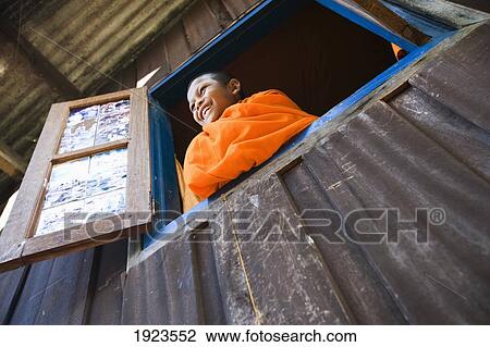 Stock Image - Novice Monk Looking Out Of Window At Vang Vieng, Laos. Fotosearch