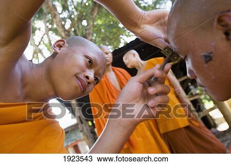 Stock Image - Novice Monks Having Their Heads Shaved At Wat Naluang, Luang Prabang, Northern Laos. Fotosearch