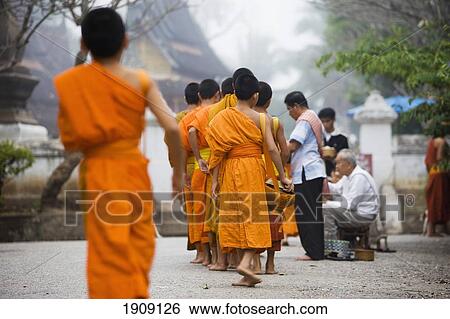 Stock Photograph - Novice Monks Out Collecting Alms At Dawn In Luang Prabang, Laos. Fotosearch