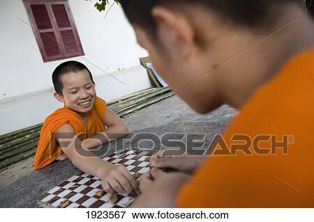 Stock Photo - Novice Monks Relaxing Playing Checkers, Luang Prabang, Northern Laos. Fotosearch