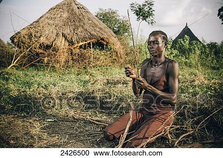 Stock Image - Nuer woman preparing firewood, near Gambella, Western Ethiopia; Ethiopia. Fotosearch