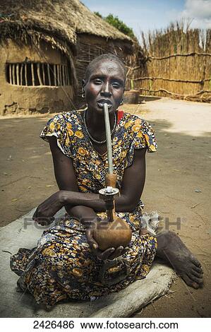 Stock Photograph - Nuer Woman smoking traditional pipe, Western Ethiopia; Ethiopia. Fotosearch