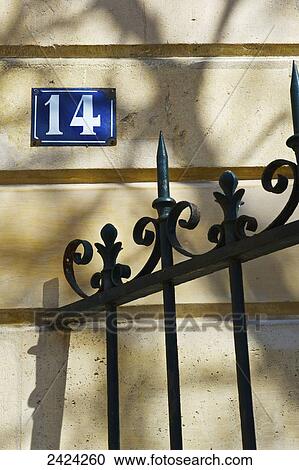Stock Image - Number fourteen sign and an ornate railing against a building, Marais district; Paris, France. Fotosearch