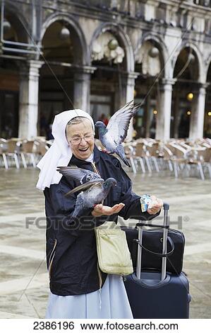 Nun feeding pigeons in Piazza San Marco; Venice, Veneto, Italy View Large Photo Image Stock Photograph - Nun feeding pigeons in Piazza San Marco; Venice, Veneto, Italy. Fotosearch
