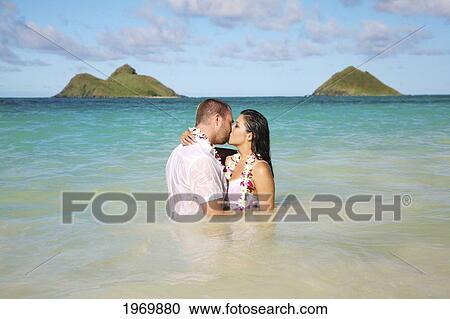 Stock Image - Oahu, Hawaii, Lanikai, Young Couple Both Holding Eachother And Kissing.. Fotosearch