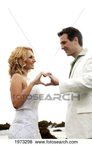Stock Photo - Oahu, Hawaii, Wedding Couple Smiling At Each Other, Hands In The Shape Of A Heart.. Fotosearch