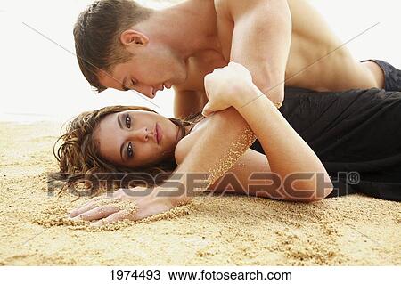 Stock Image - Oahu, Hawaii, Young Couple Laying On The Beach.. Fotosearch