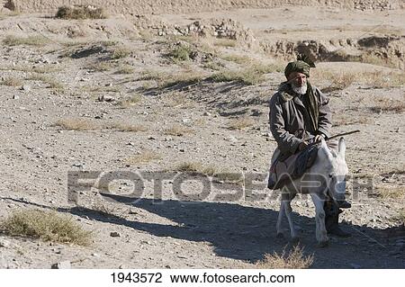 Stock Image - Old Afghan Man On A Donkey In Pol-E Matak, Parwan Province, Afghanistan. Fotosearch
