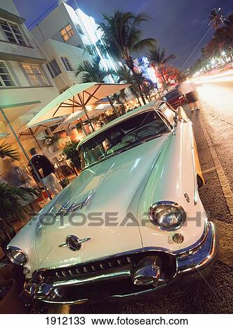 Stock Image - Old American Car Parked Outside Cafes And Hotels On Ocean Drive, South Beach, Miami, Florida, Usa.. Fotosearch