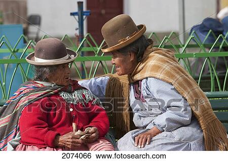 Stock Photograph - Old Aymara Women Chatting On A Park Bench In San Pedro De Tiquina, La Paz Department, Bolivia. Fotosearch